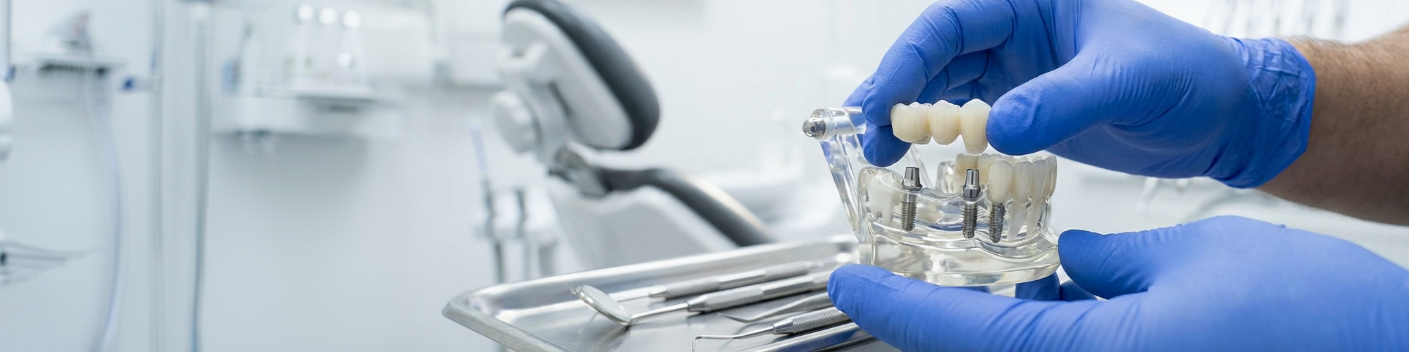 Gloved hands placing dental bridge on dental implants.